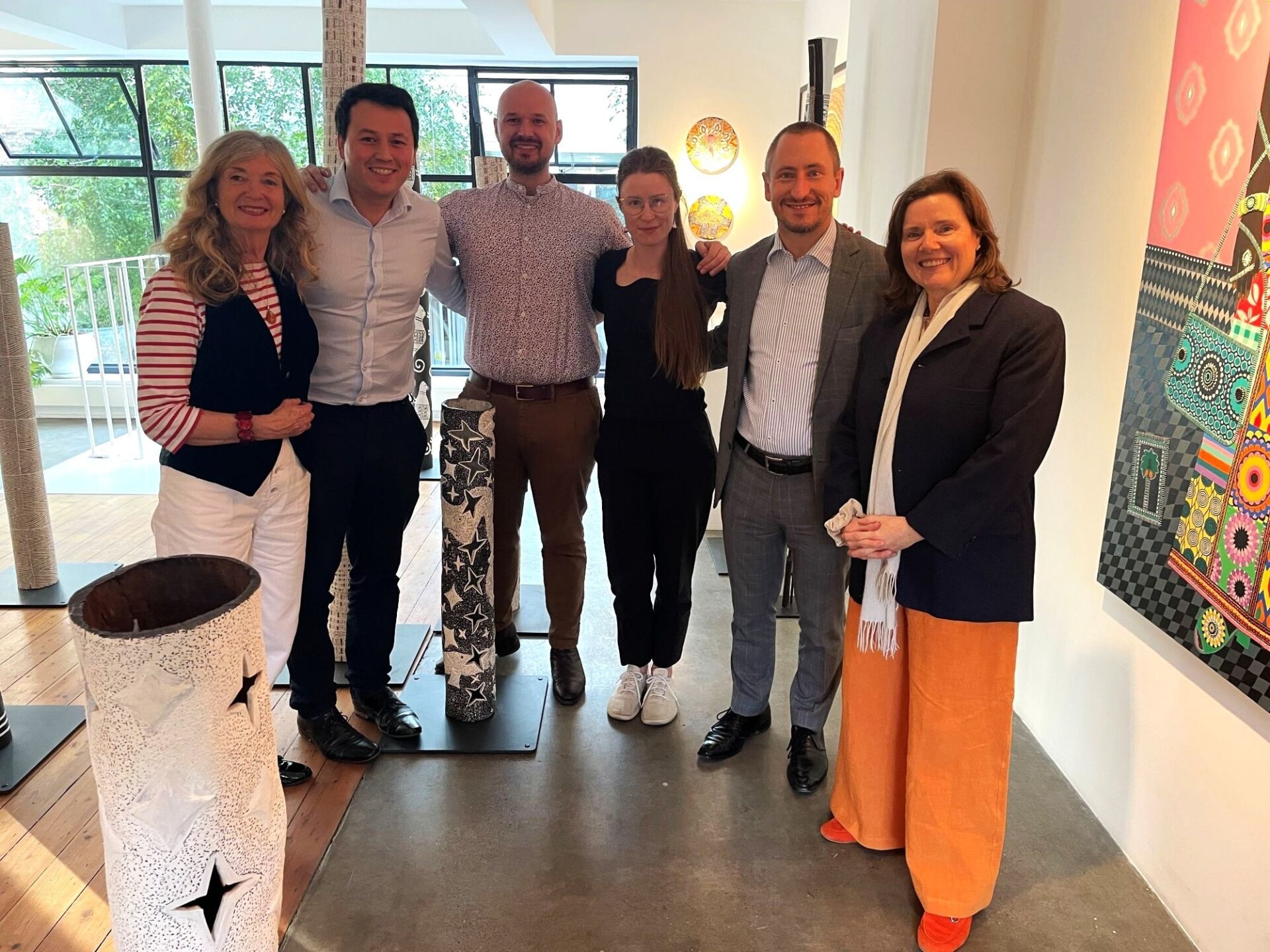 Six Burgmann alumni and friends stand together inside the Rebecca Hossack Art Gallery, London.