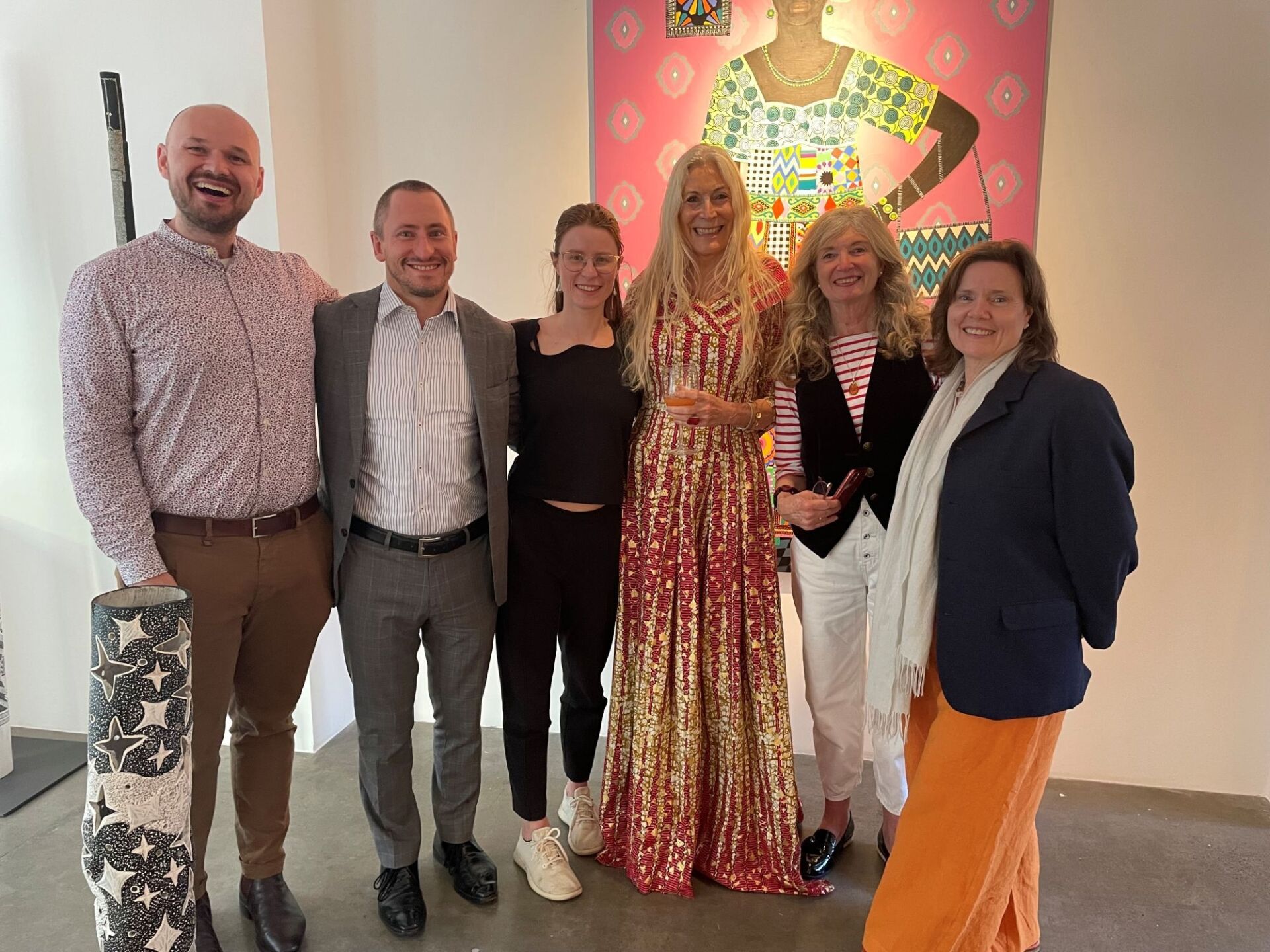 Six Burgmann alumni and friends stand in front of an artwork at the Rebecca Hossack Art Gallery, London.